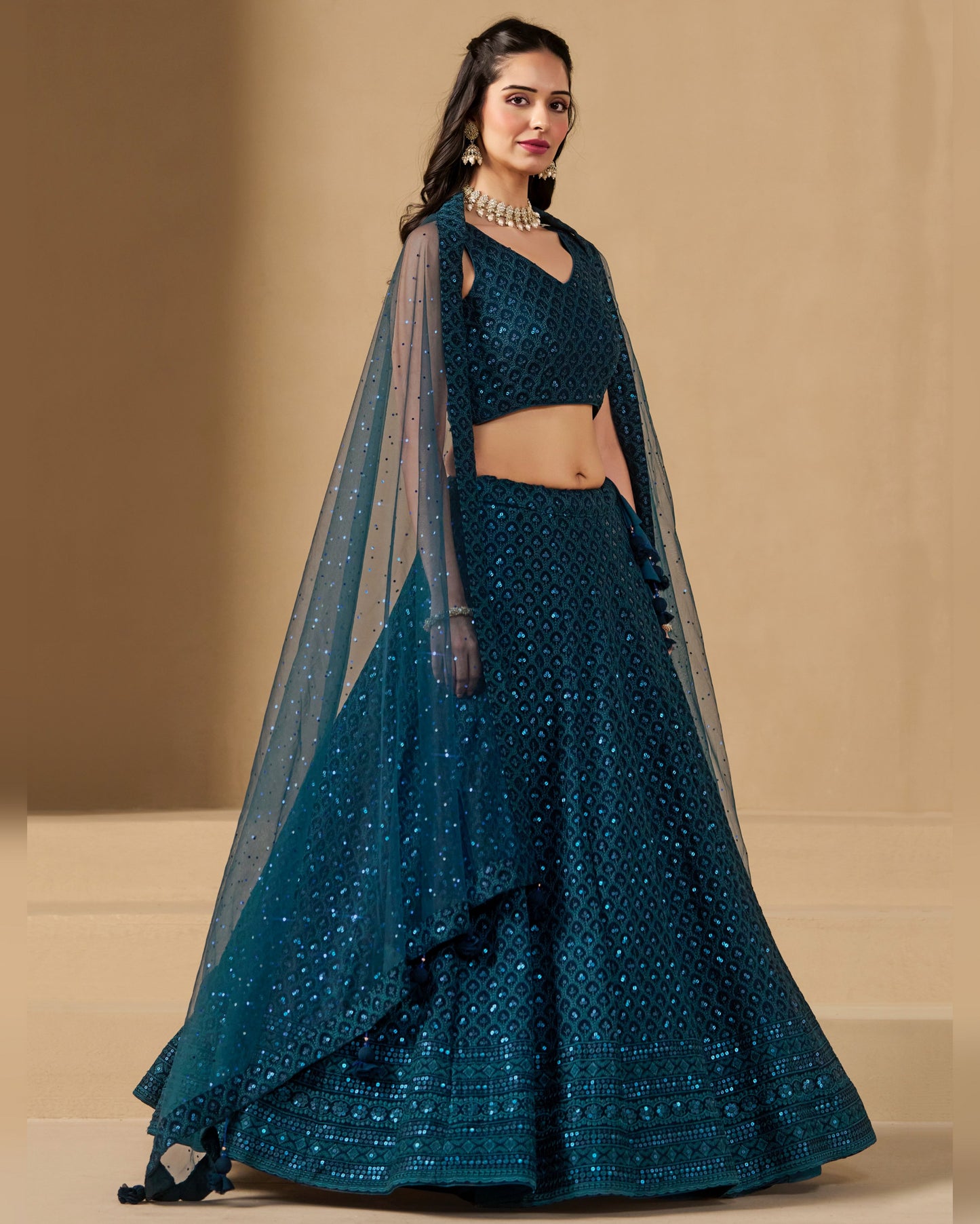 Teal lehenga with matching blouse and dupatta on a beige background