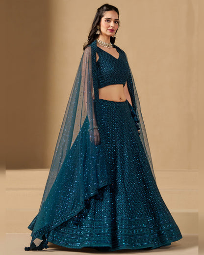 Teal lehenga with matching blouse and dupatta on a beige background