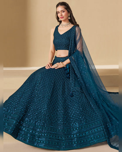 Woman wearing a blue embroidered lehenga with a matching blouse on a beige background