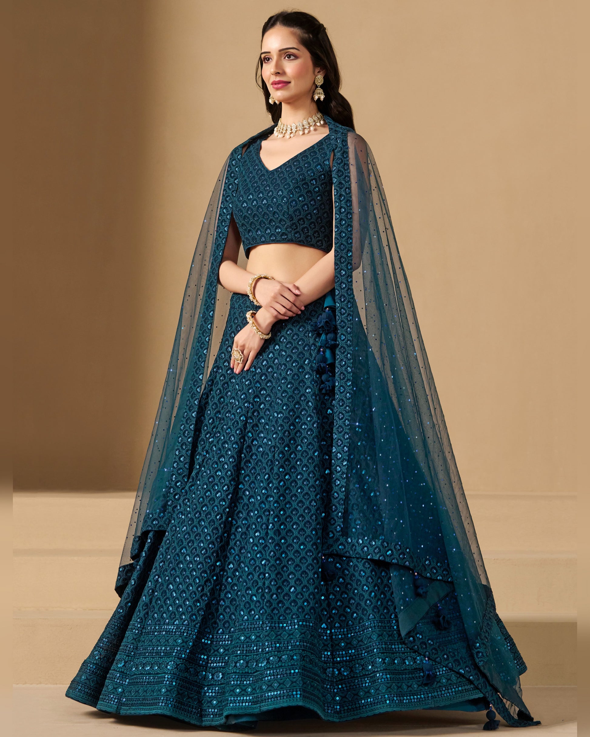 Teal traditional outfit with a matching dupatta on a beige background