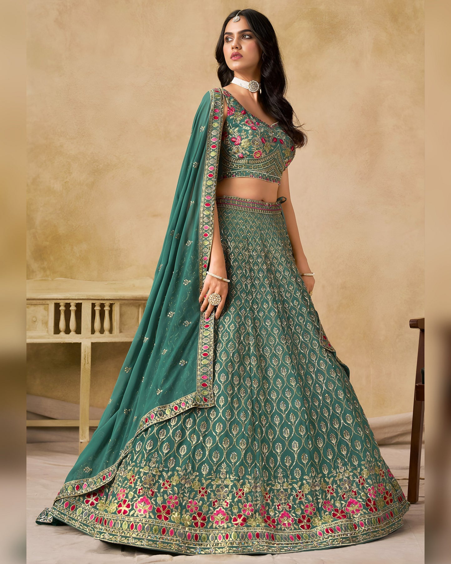 Woman wearing a green embroidered lehenga with a beige background