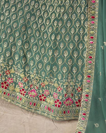 Teal fabric with intricate gold and pink floral embroidery on a beige background
