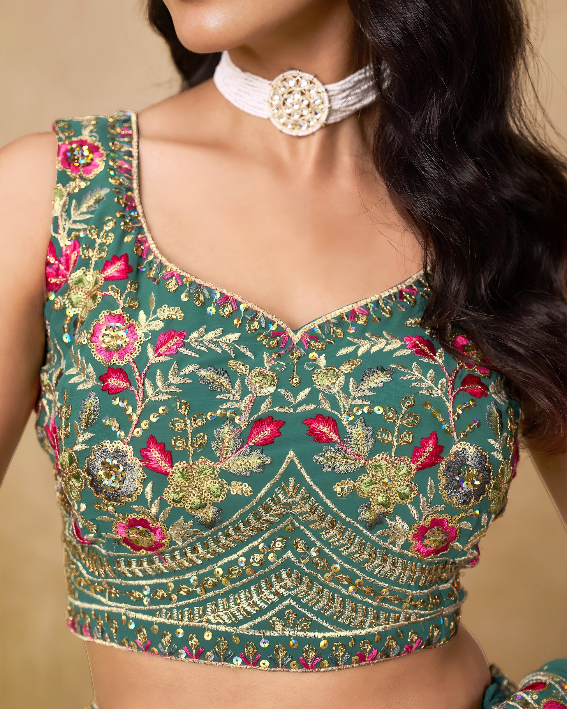 Green embroidered blouse with floral patterns on a beige background