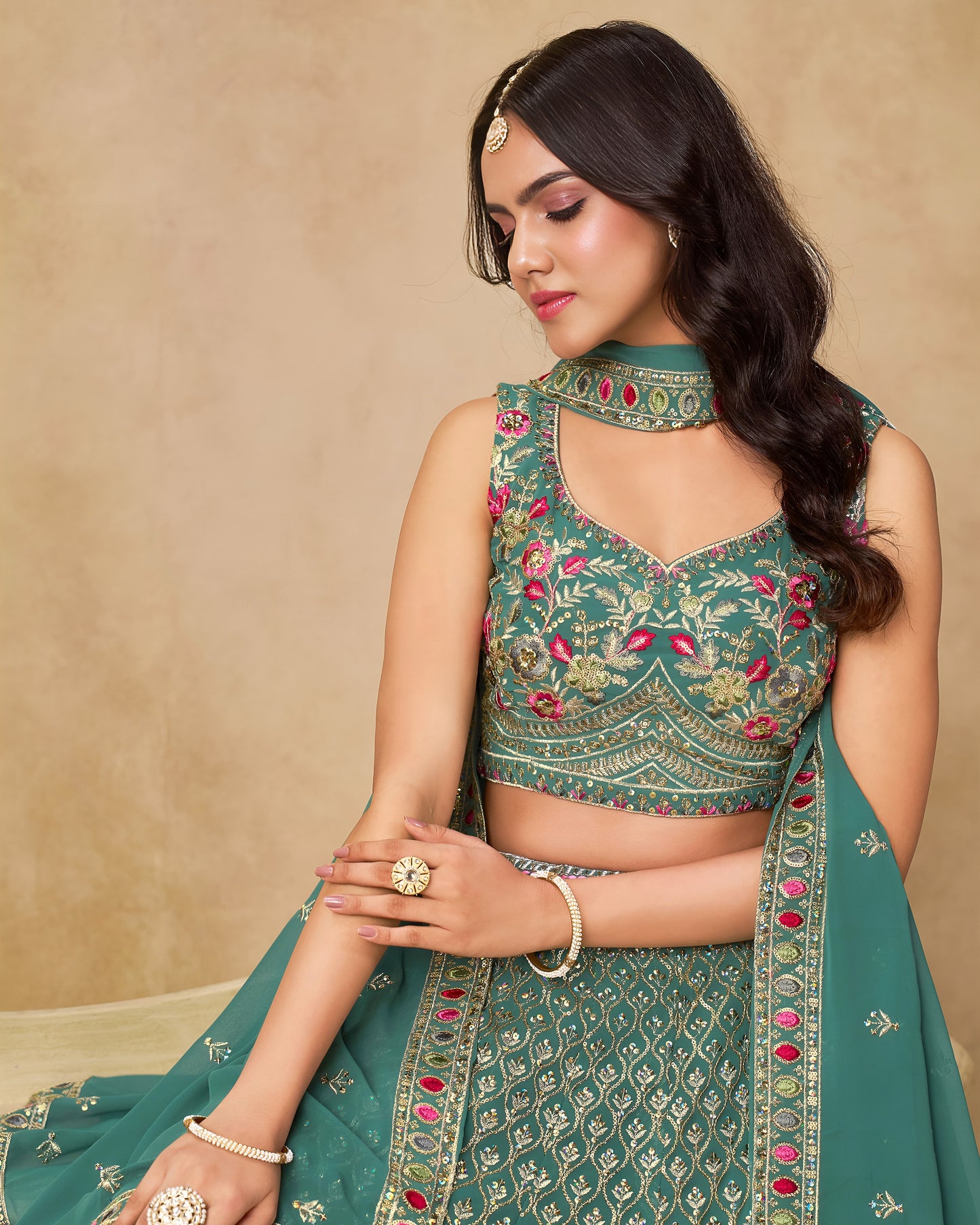 Woman wearing a green embroidered traditional outfit with a beige background
