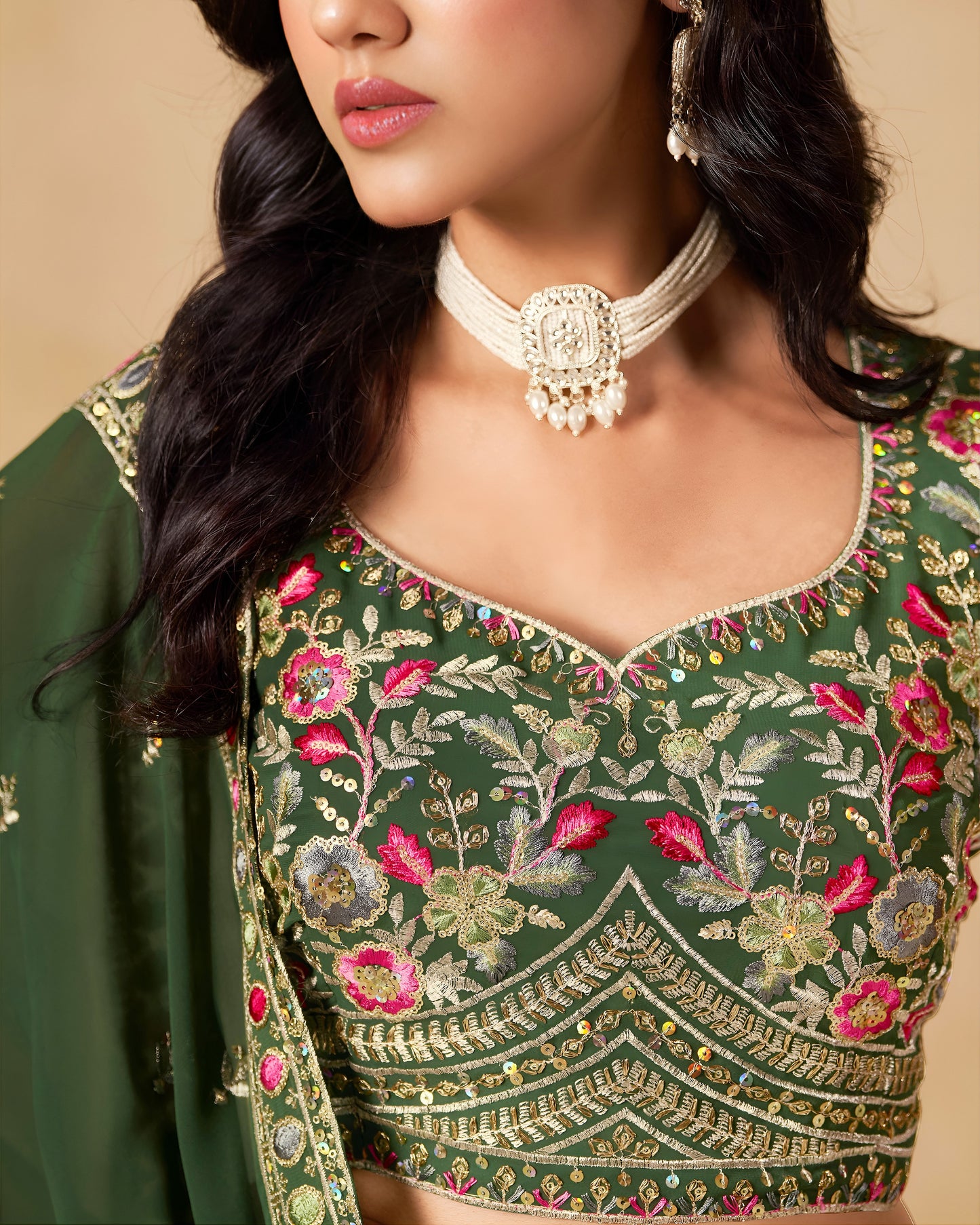 Green embroidered blouse with floral patterns worn by a person.