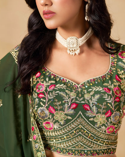 Green embroidered blouse with floral patterns worn by a person.