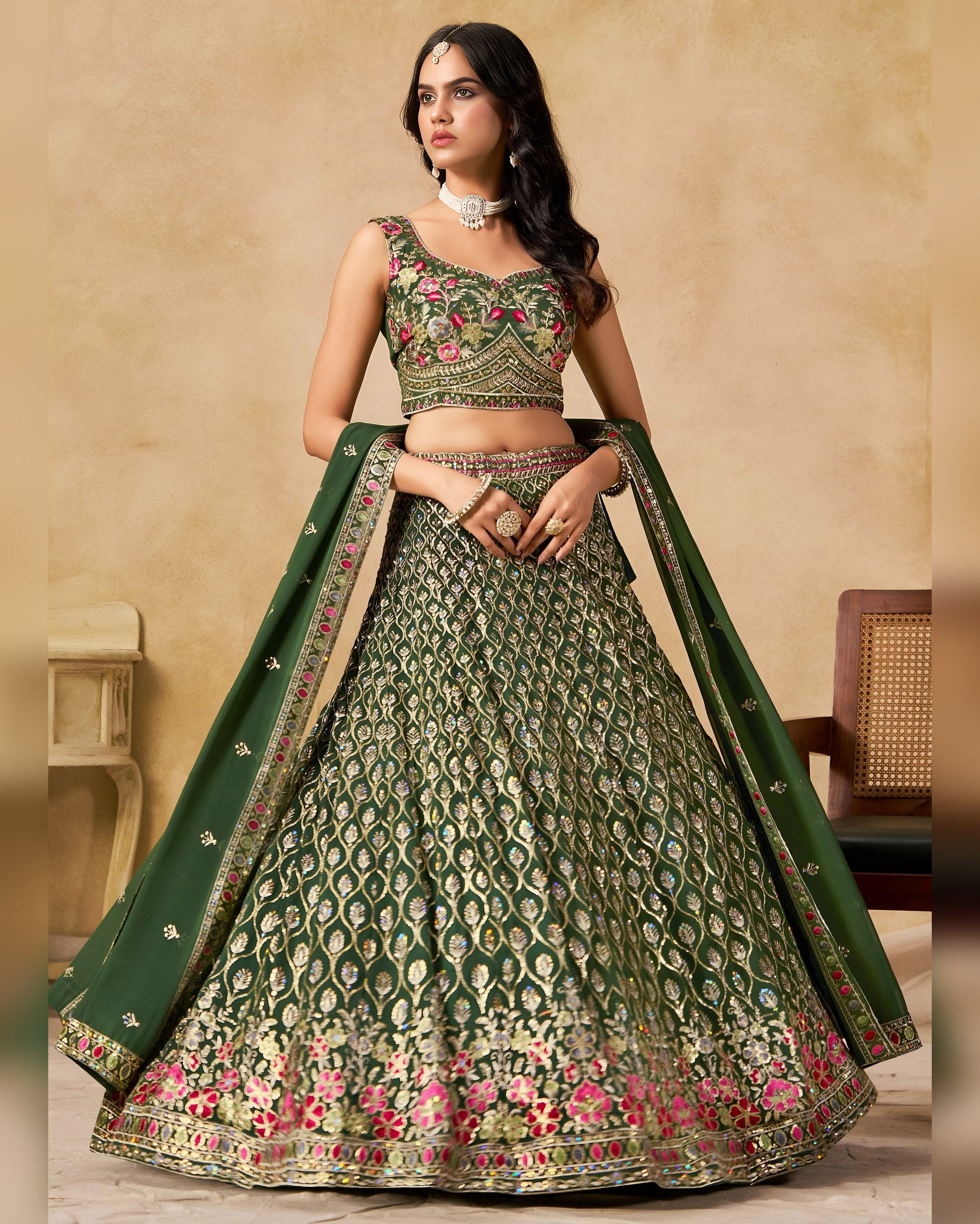 Woman wearing a green and pink embroidered traditional outfit with a beige background