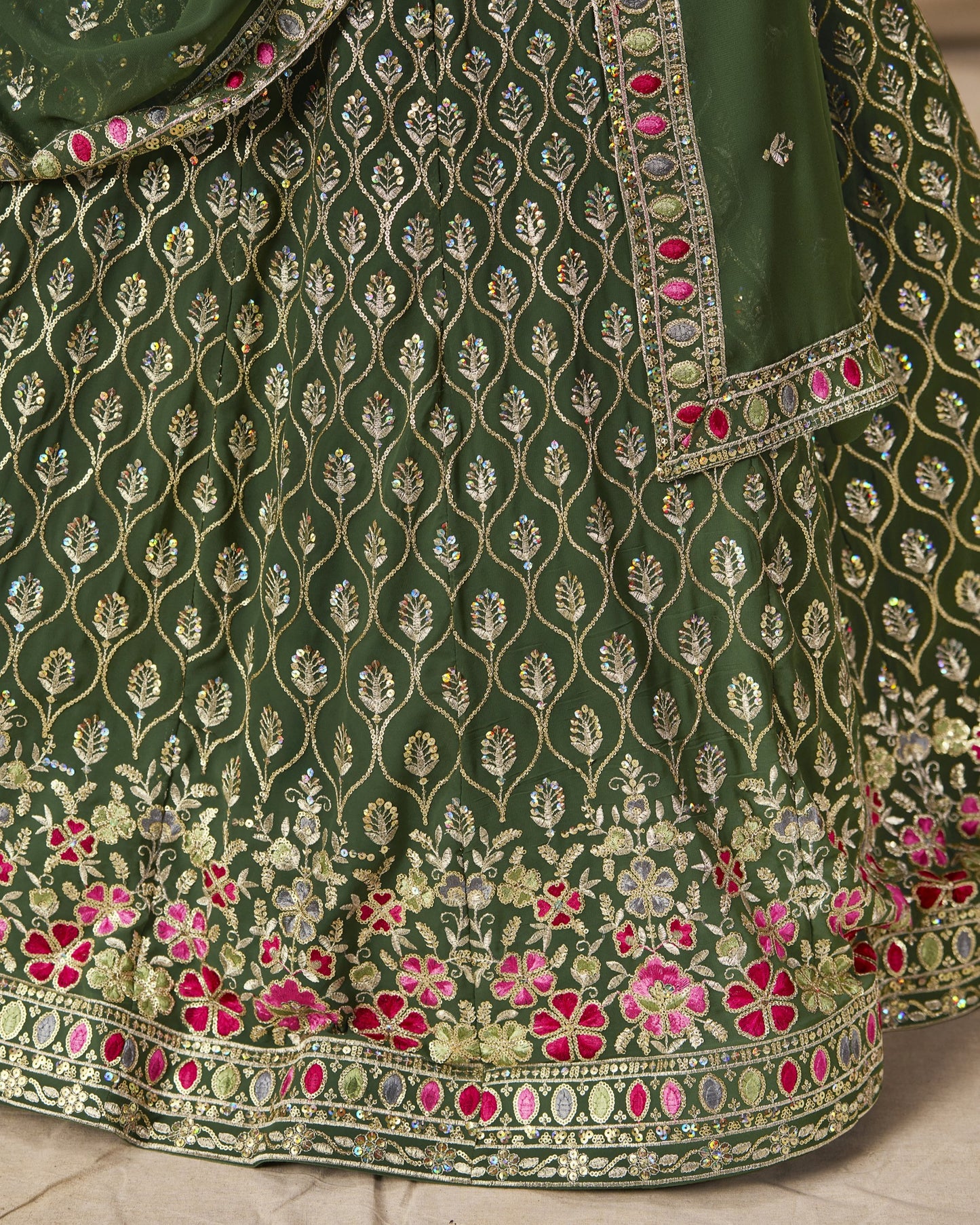Green embroidered fabric with floral patterns on a neutral background