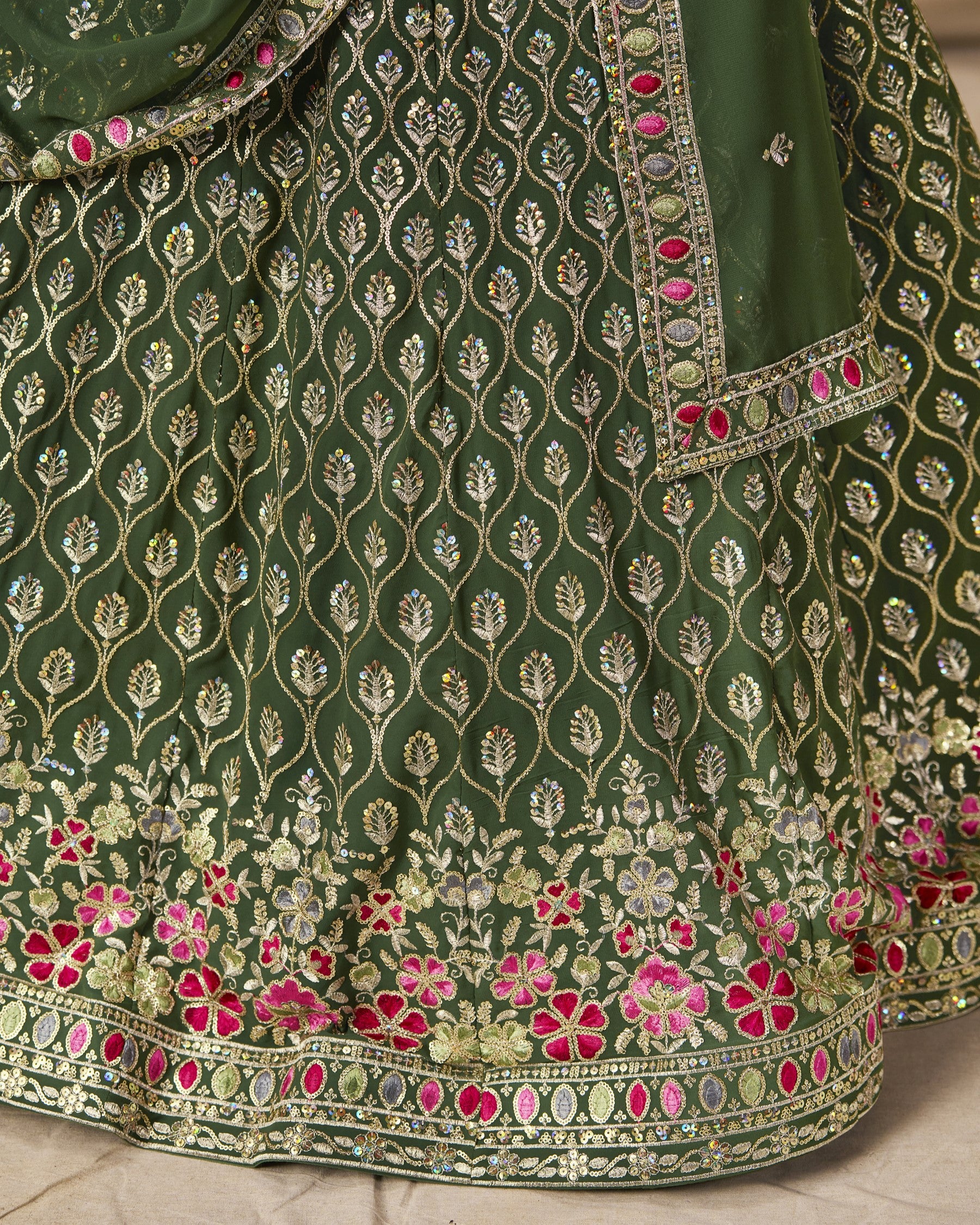Green embroidered fabric with floral patterns on a neutral background
