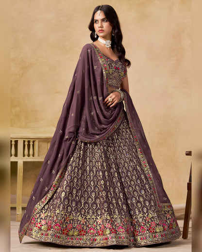 Woman wearing a traditional outfit with a purple dupatta and embroidered skirt on a beige background