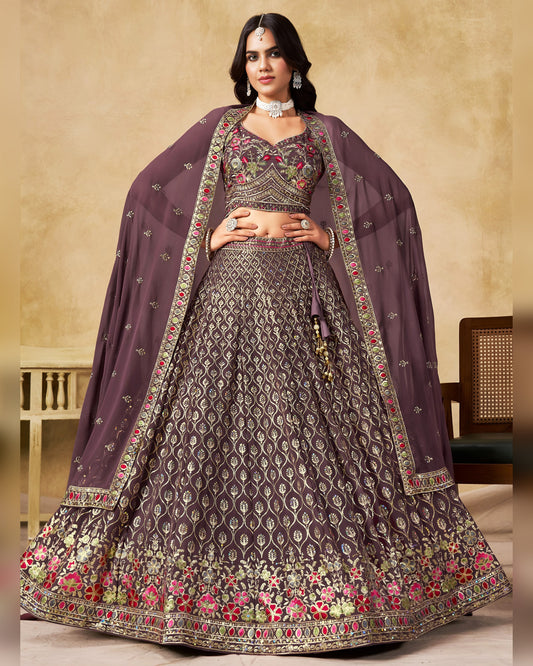Woman wearing a traditional embroidered outfit with a purple dupatta against a beige background