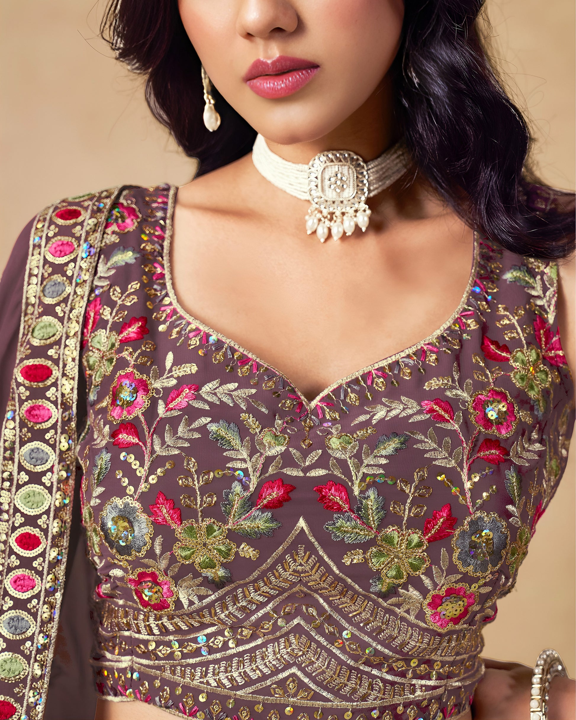 Woman wearing a intricately designed blouse with floral patterns and embroidery.
