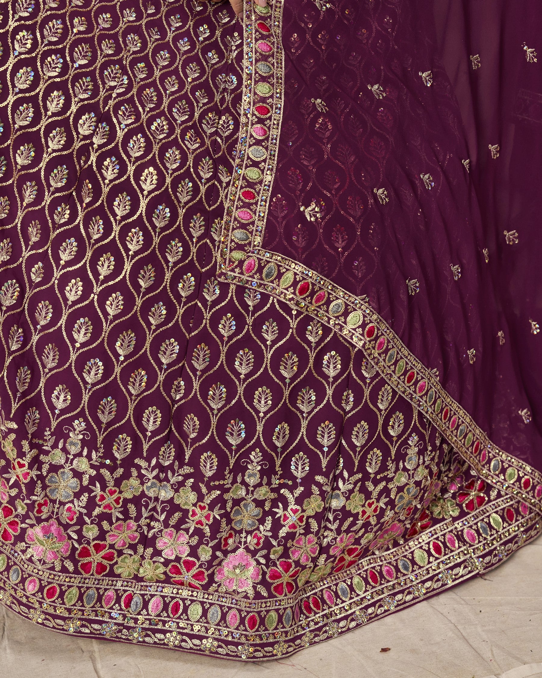 Close-up of a purple embroidered fabric with floral patterns on a light background