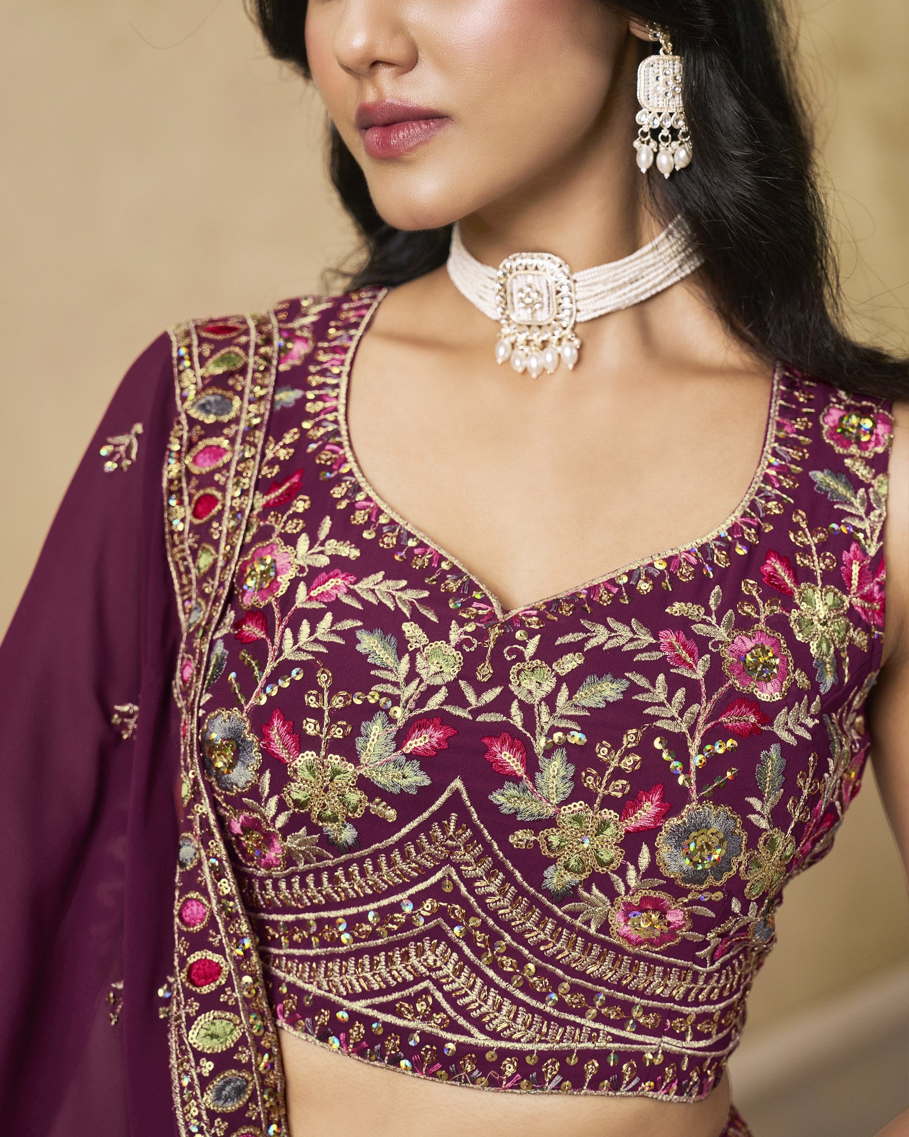 Close-up of a person wearing a purple embroidered blouse with floral patterns.