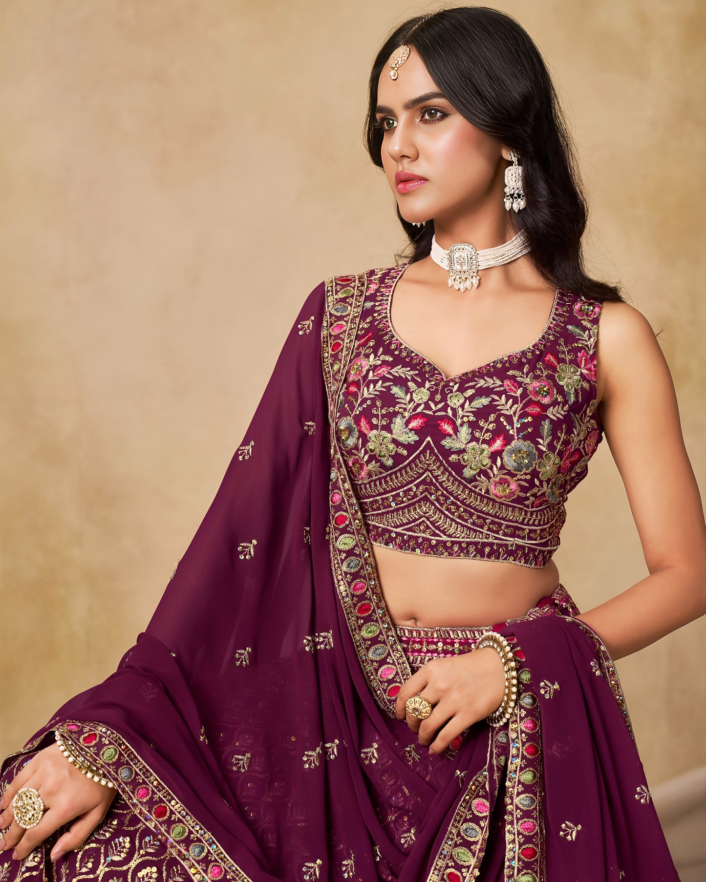 Woman wearing a traditional purple embroidered outfit with a beige background