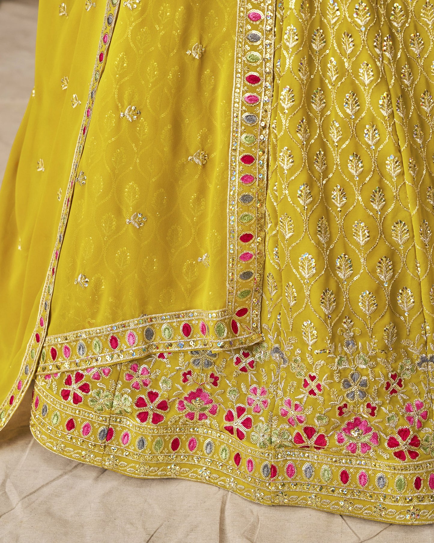 Yellow embroidered fabric with floral patterns on a neutral background