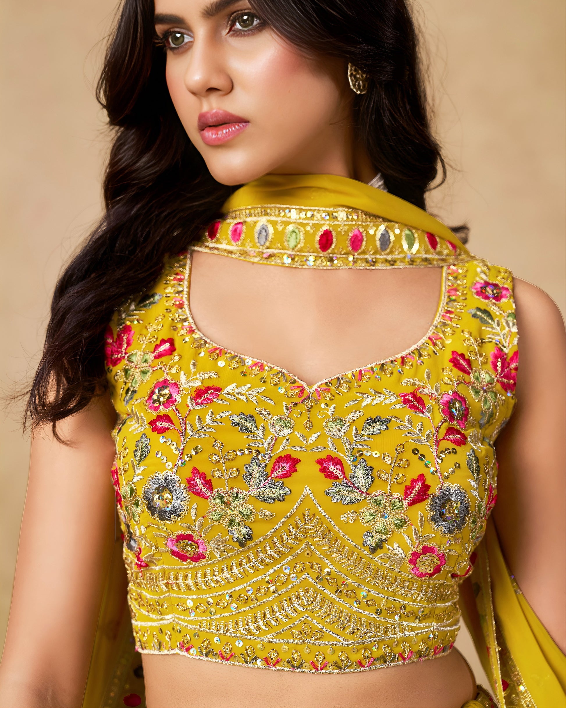 Woman wearing a yellow embroidered blouse with a beige background