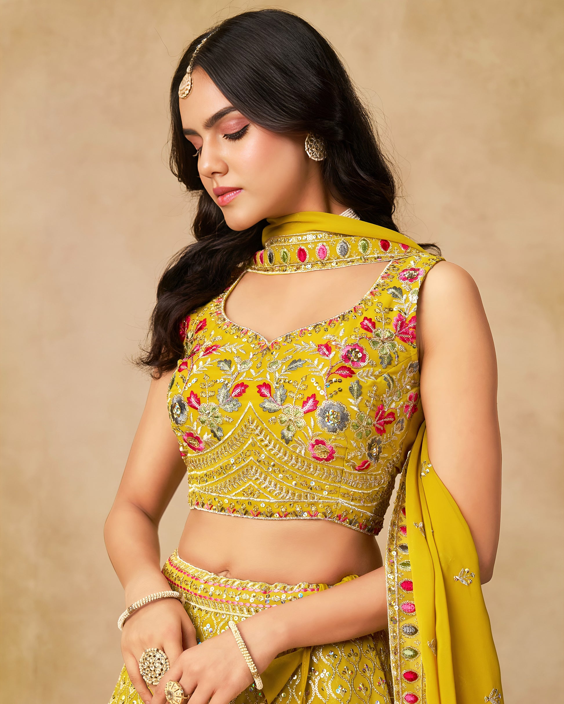 Woman wearing a yellow embroidered traditional outfit on a beige background