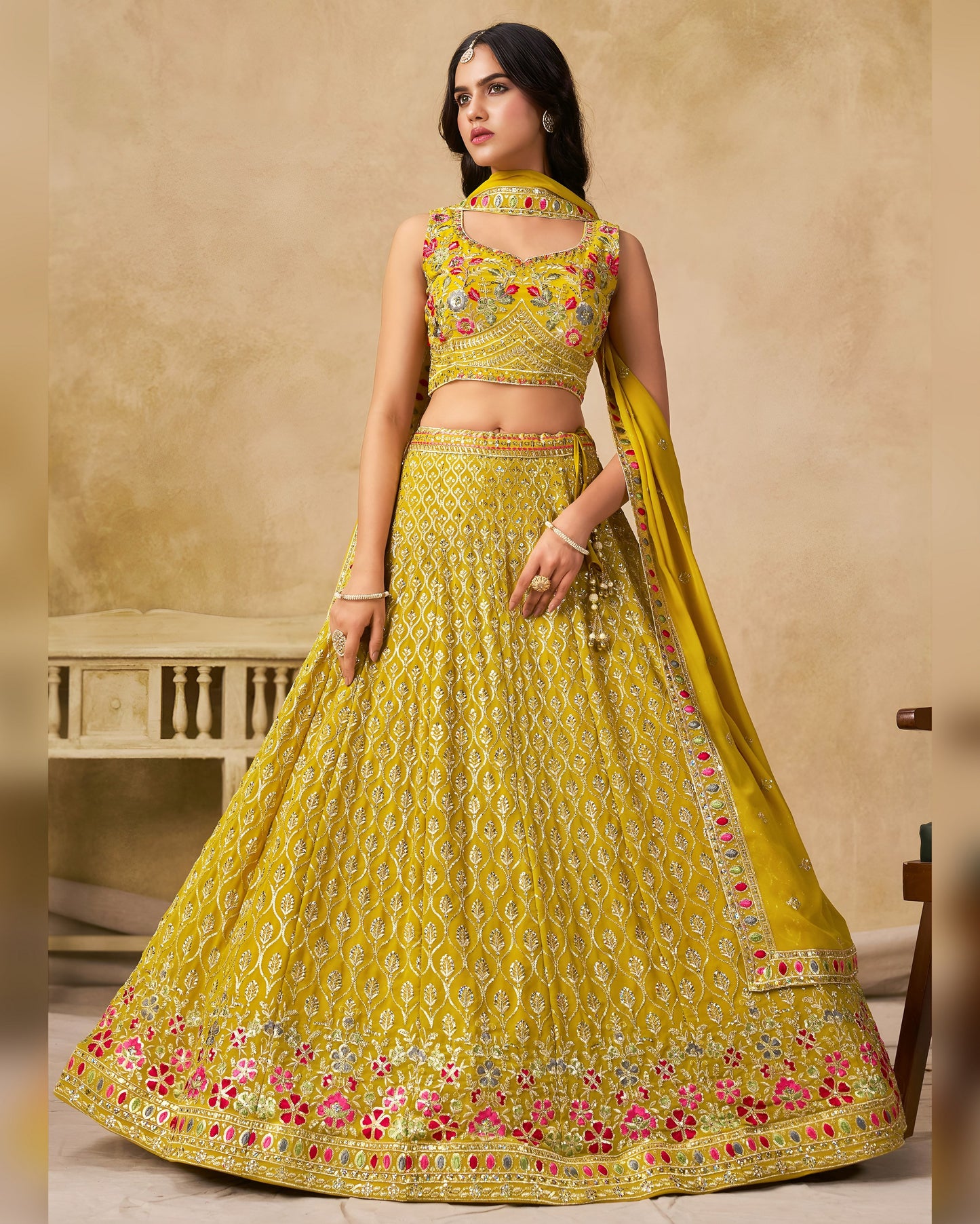 Woman wearing a yellow embroidered traditional outfit with a beige background