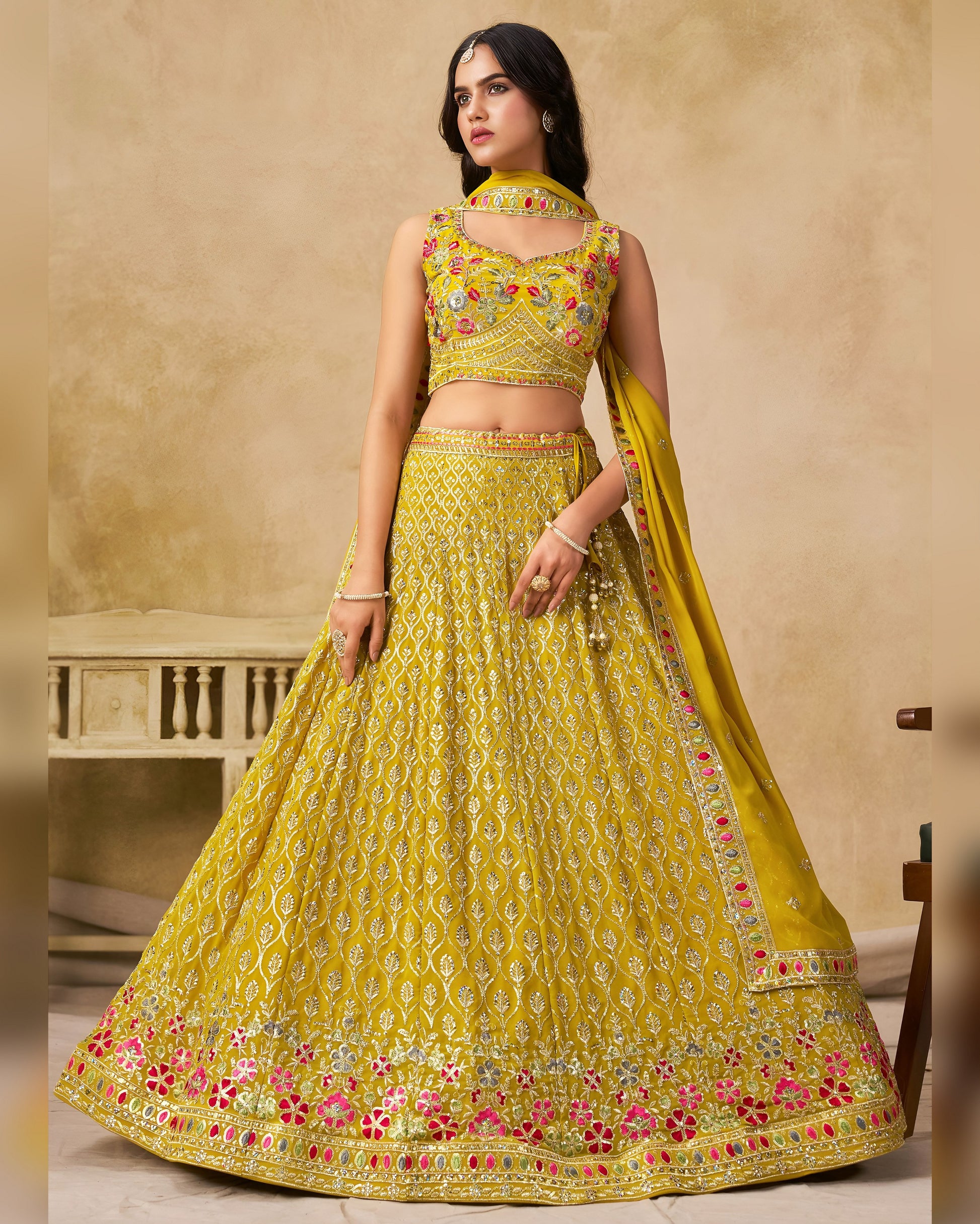 Woman wearing a yellow embroidered traditional outfit with a beige background