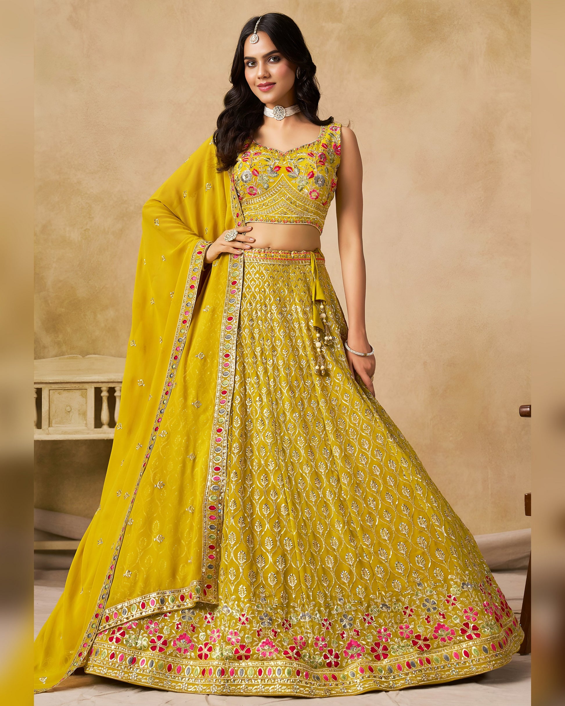 Woman wearing a yellow embroidered traditional outfit with a beige background