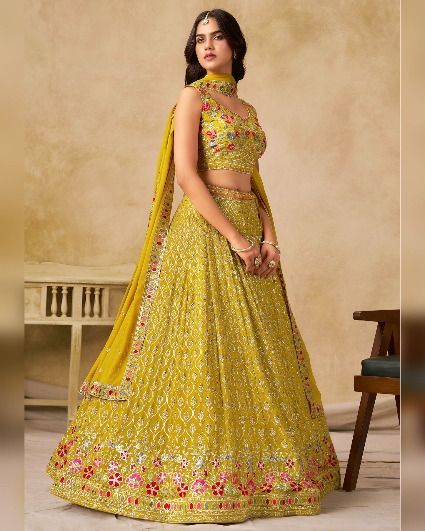 Woman wearing a yellow embroidered traditional outfit with a beige background
