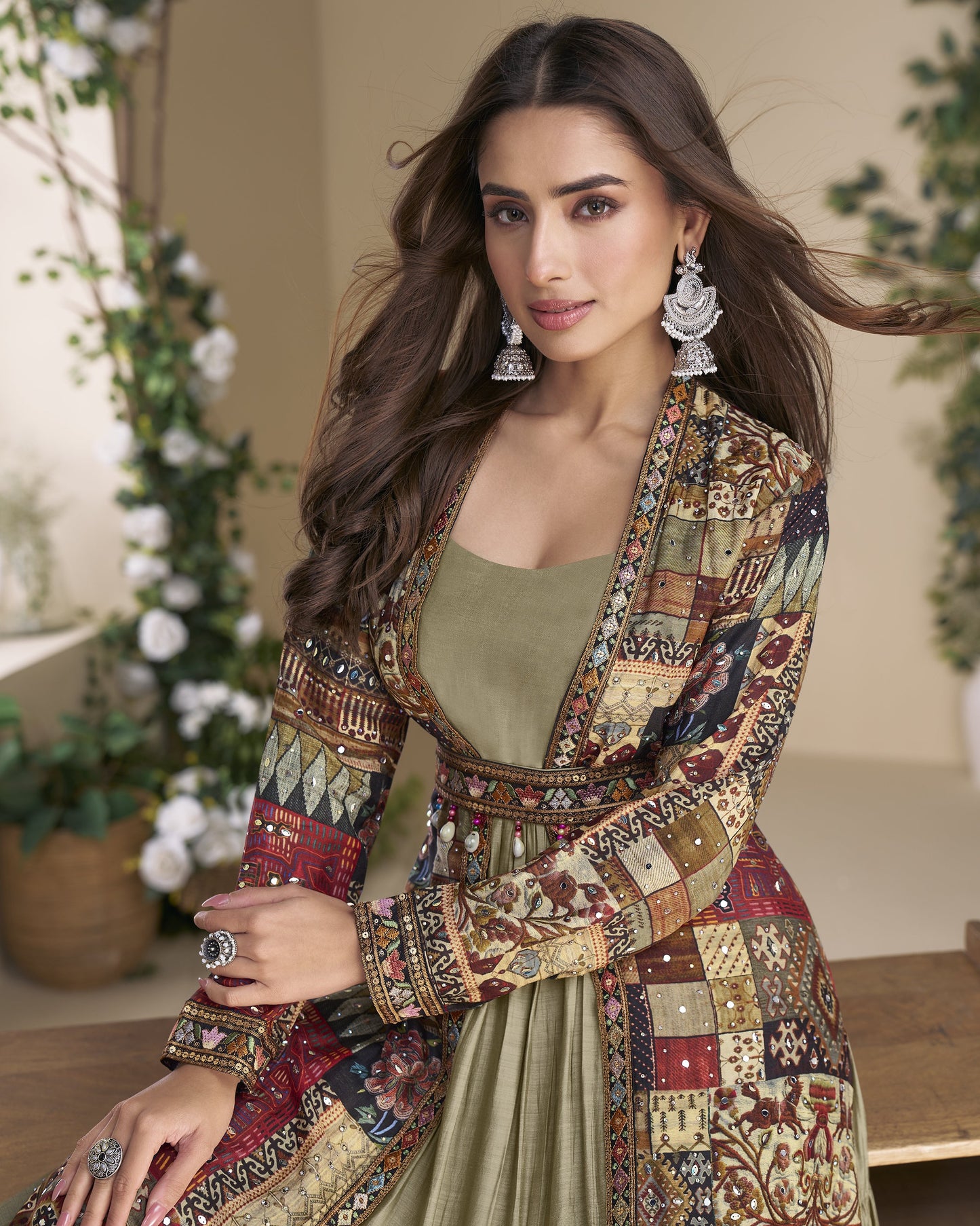 Woman wearing a patterned jacket and green top in an indoor setting with plants.
