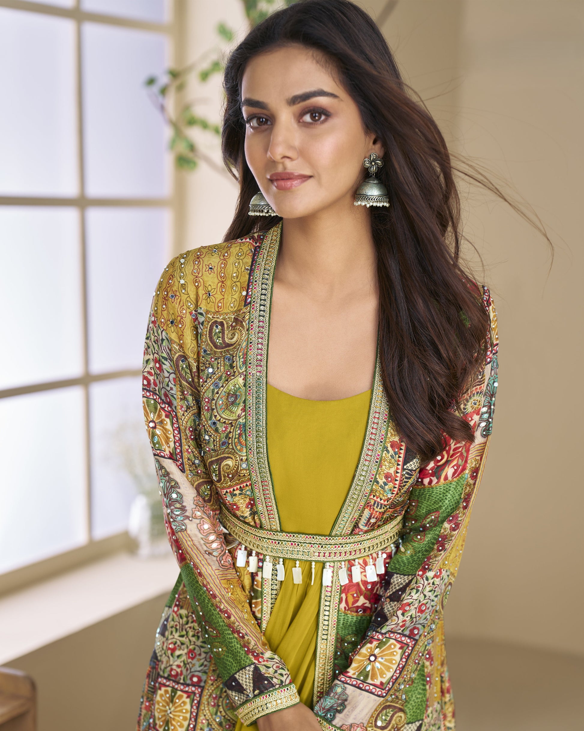Woman wearing a colorful, patterned outfit with a yellow top indoors.
