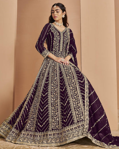 Woman wearing a purple and gold embroidered traditional outfit against a beige background