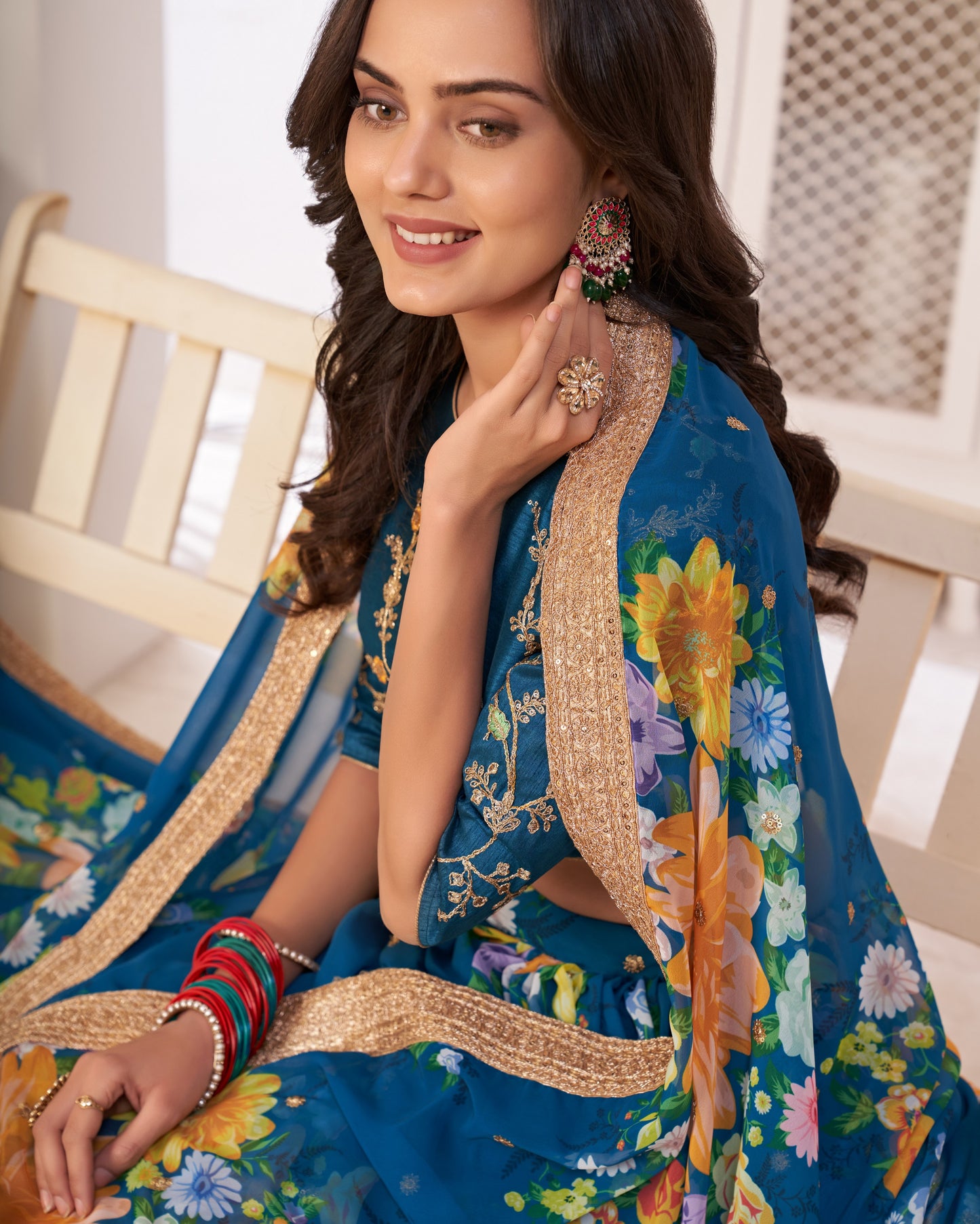 Woman wearing a blue embroidered saree with floral patterns indoors.