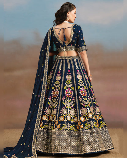 Woman wearing a navy blue embroidered lehenga with a blurred background