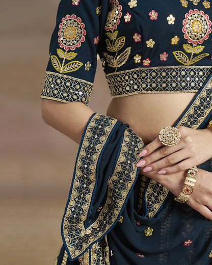 Navy blue embroidered saree with gold details and jewelry on a blurred background