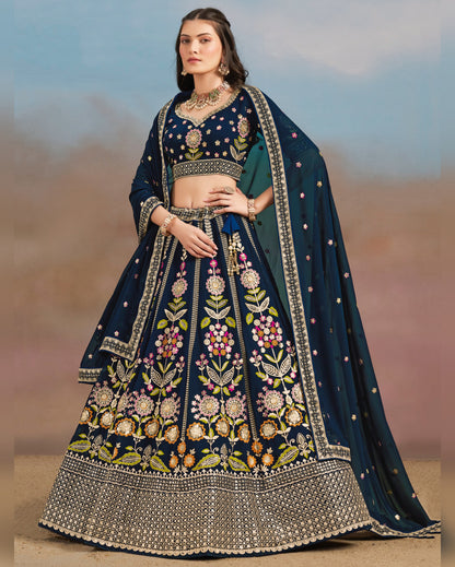 Woman wearing a traditional embroidered navy blue and green lehenga with a blurred desert background