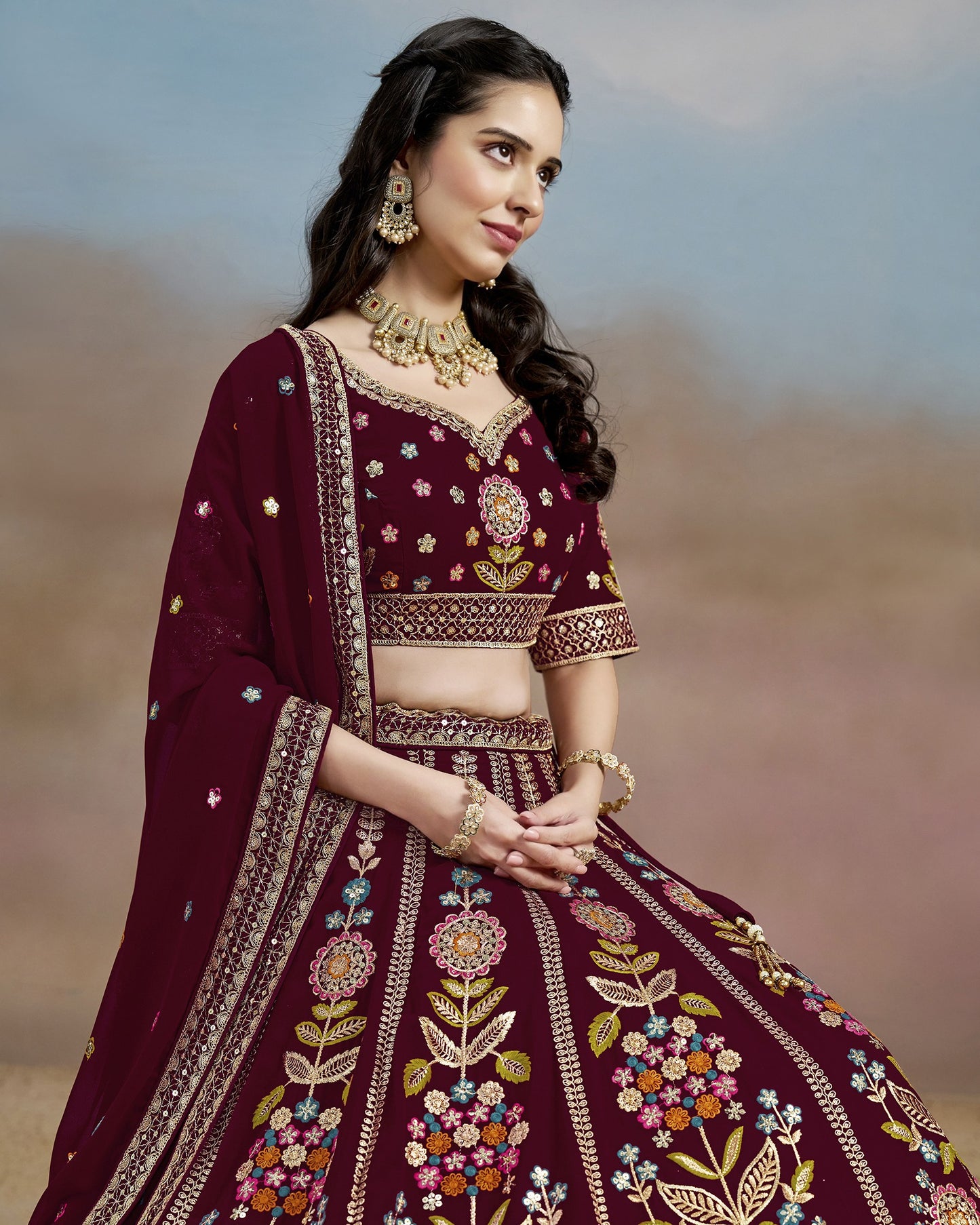 Woman in a maroon embroidered traditional outfit with a blurred background