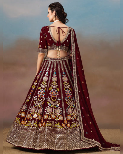 Maroon embroidered lehenga with floral patterns against a blurred natural background