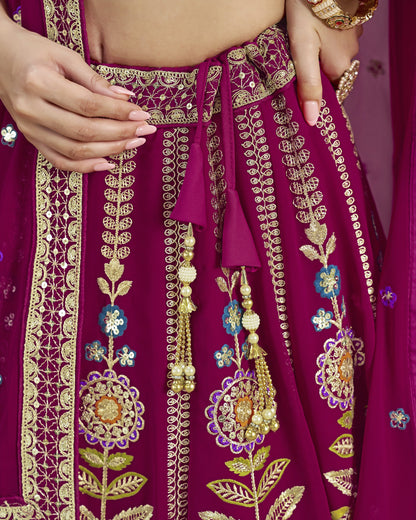 Close-up of a maroon traditional outfit with gold embroidery and floral patterns.