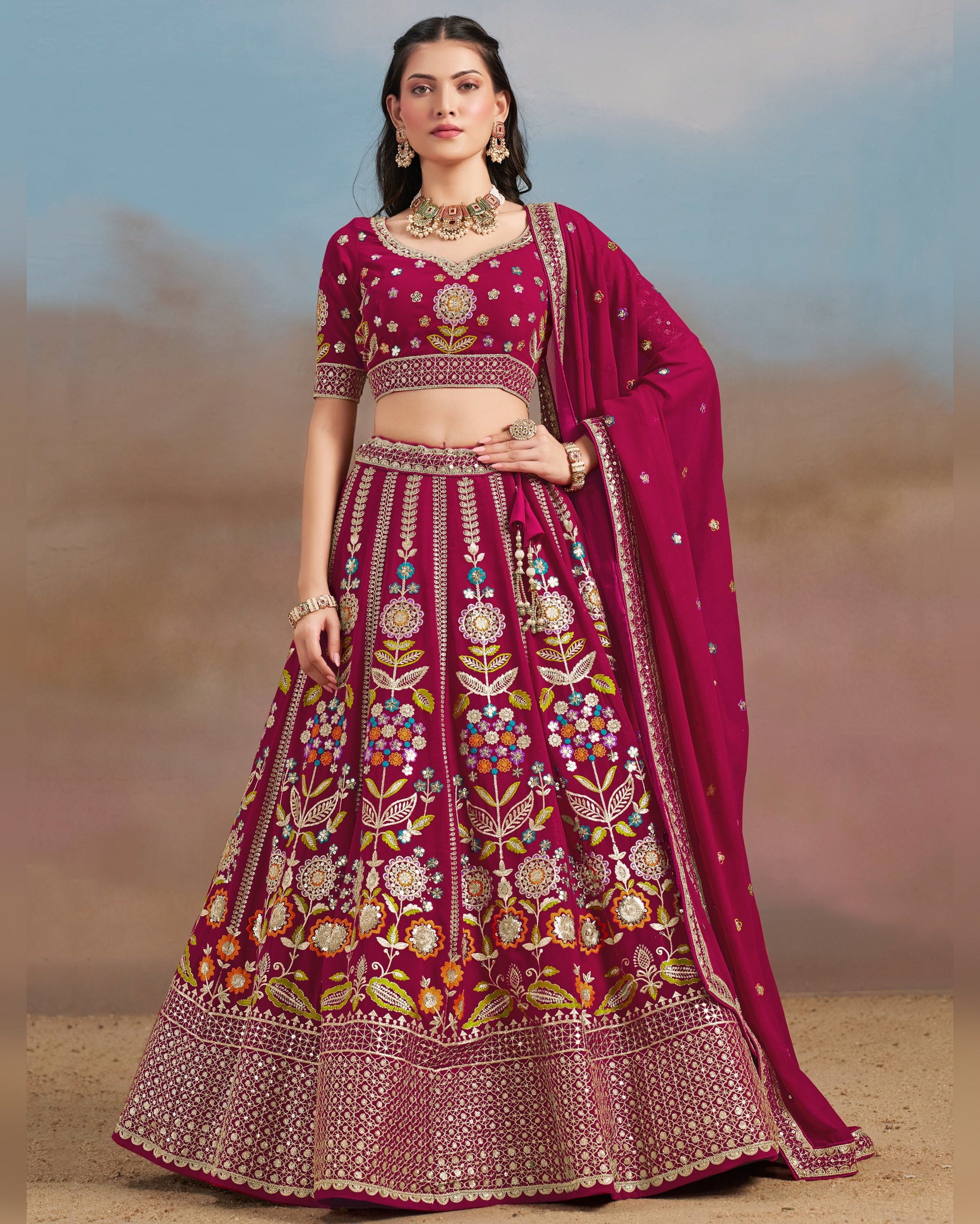 Woman wearing a traditional pink embroidered outfit with a blurred desert background