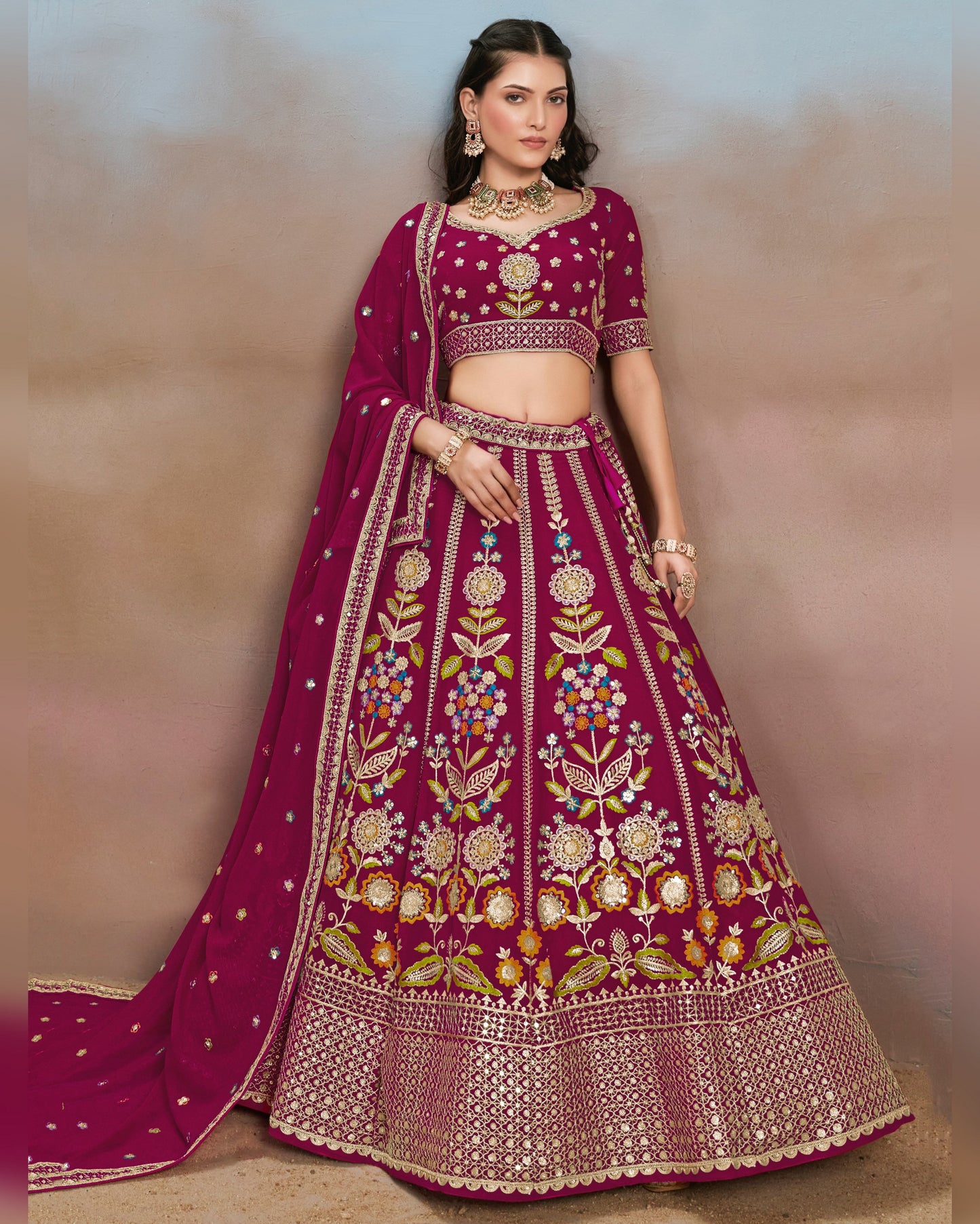Woman wearing a traditional embroidered purple lehenga with a plain background