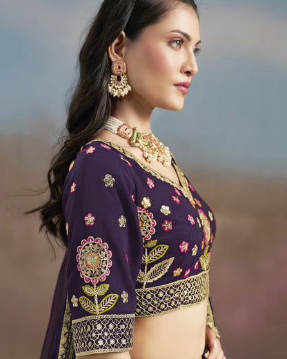 Woman wearing a purple embroidered blouse with gold jewelry against a blurred natural background