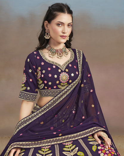 Woman wearing a traditional purple saree with floral patterns against a neutral background