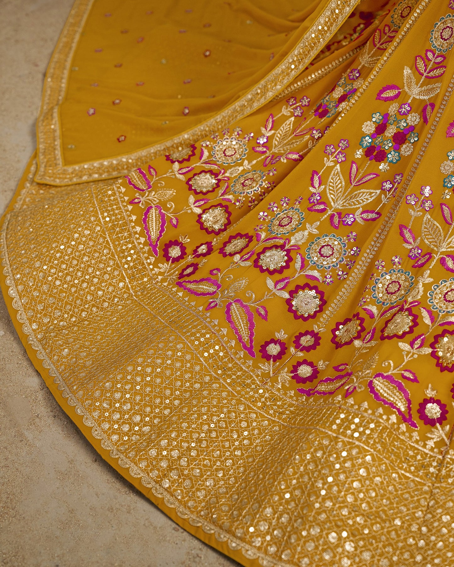 Close-up of a yellow fabric with intricate floral embroidery on a beige background
