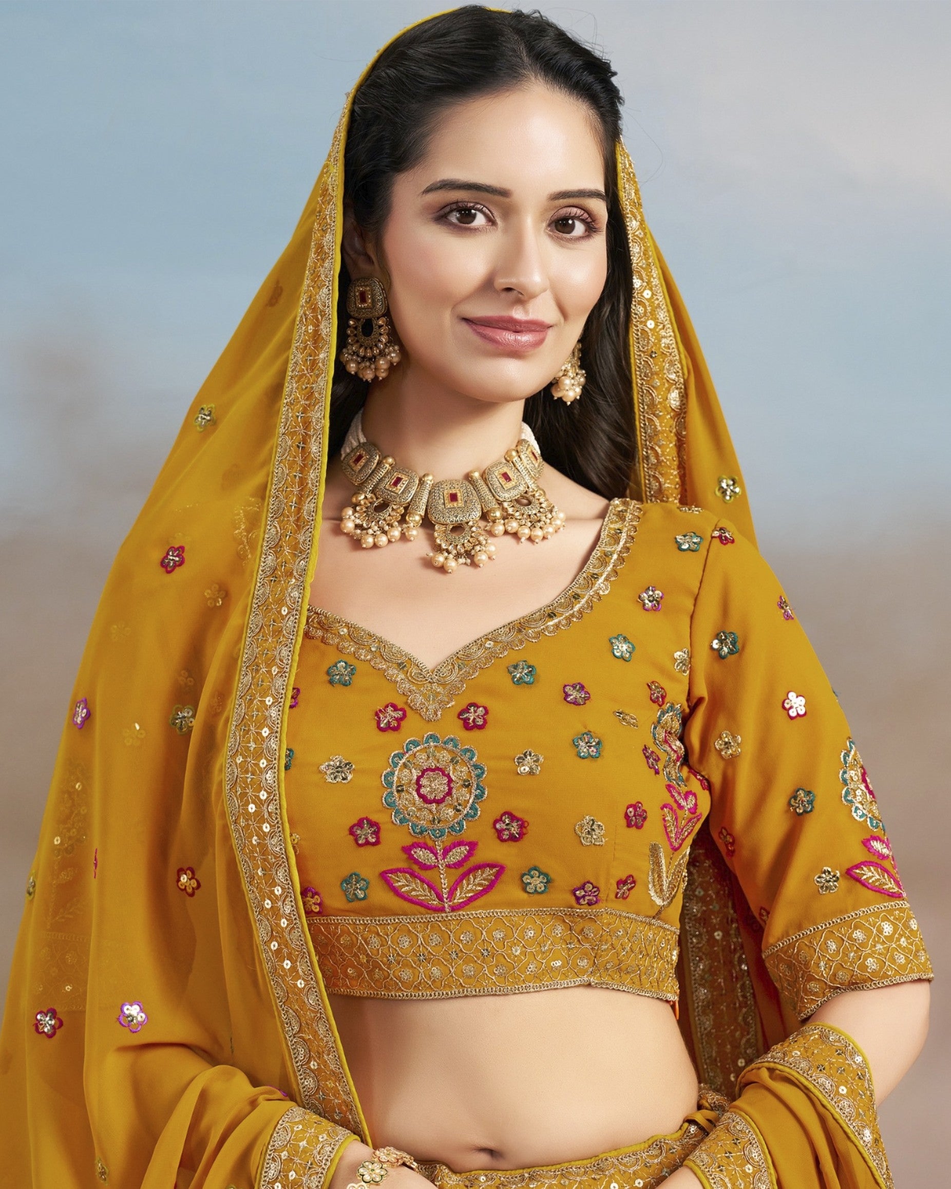 Woman wearing a yellow embroidered traditional outfit with a matching dupatta.