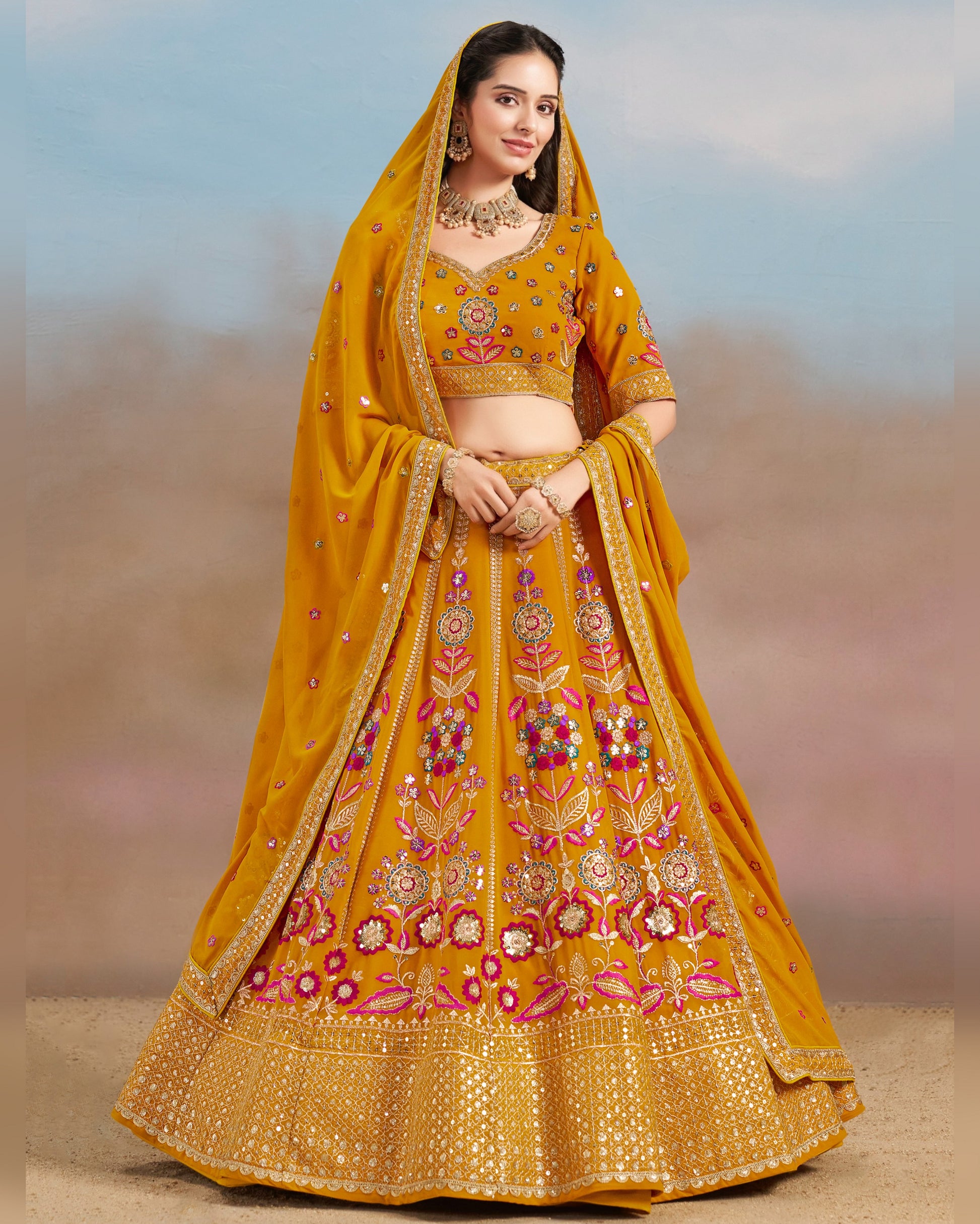 Woman wearing a yellow embroidered lehenga with a matching dupatta against a blurred background