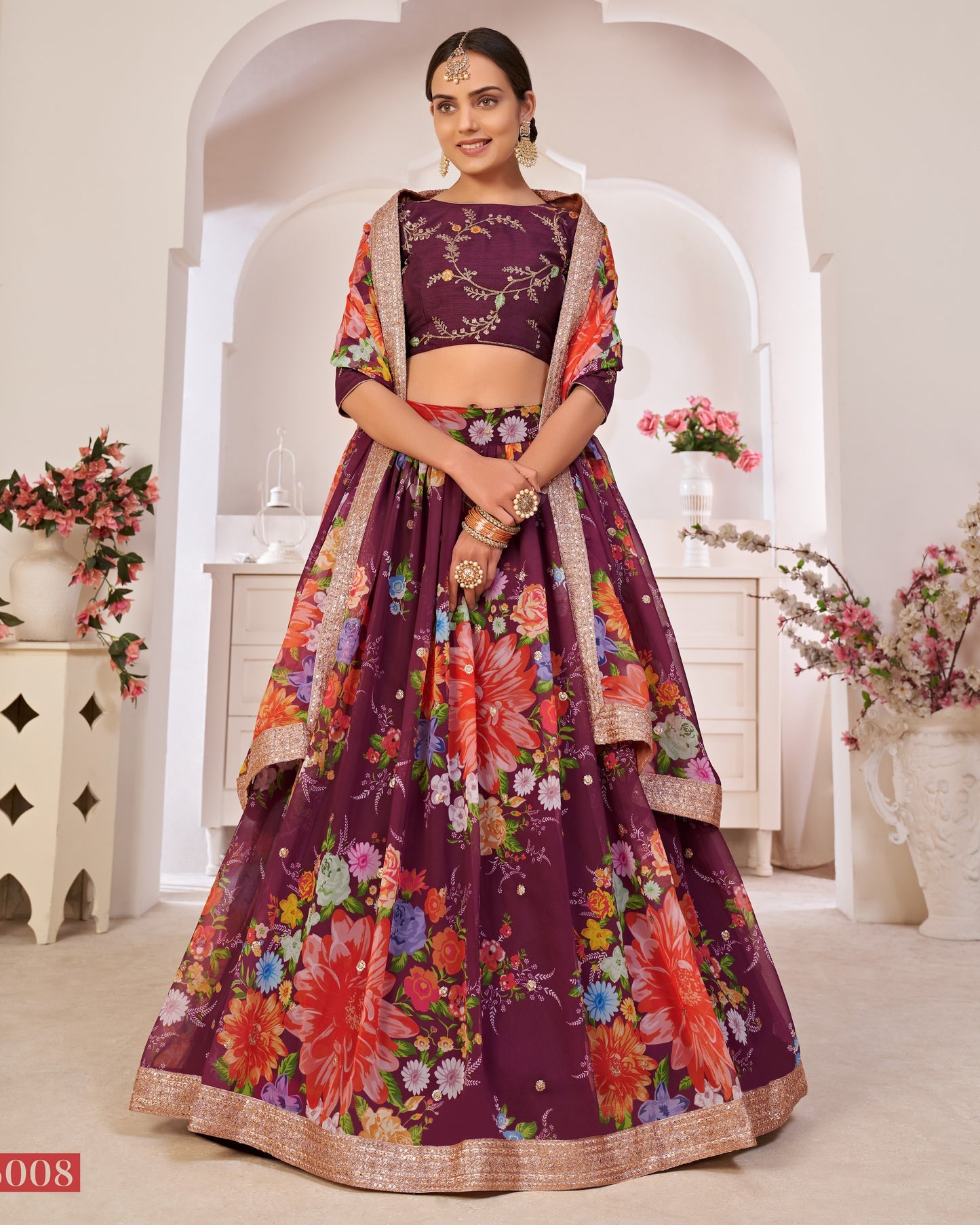 Woman wearing a vibrant floral traditional outfit in a decorated indoor setting