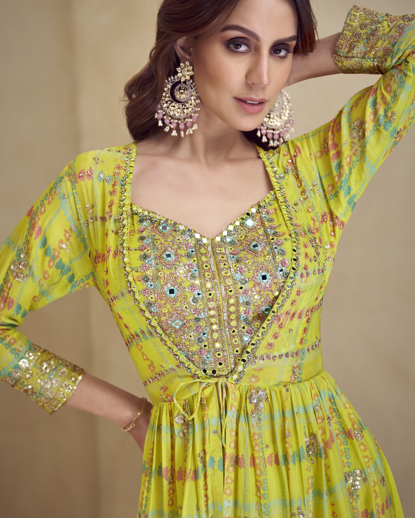 Woman wearing a yellow embroidered dress with floral patterns on a beige background