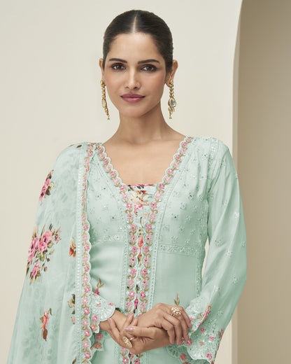 Woman wearing a light green embroidered dress with floral patterns on a neutral background