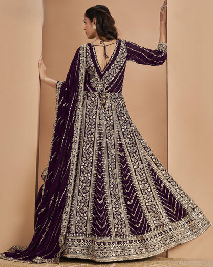 Woman wearing a purple and gold embroidered traditional outfit against a beige background