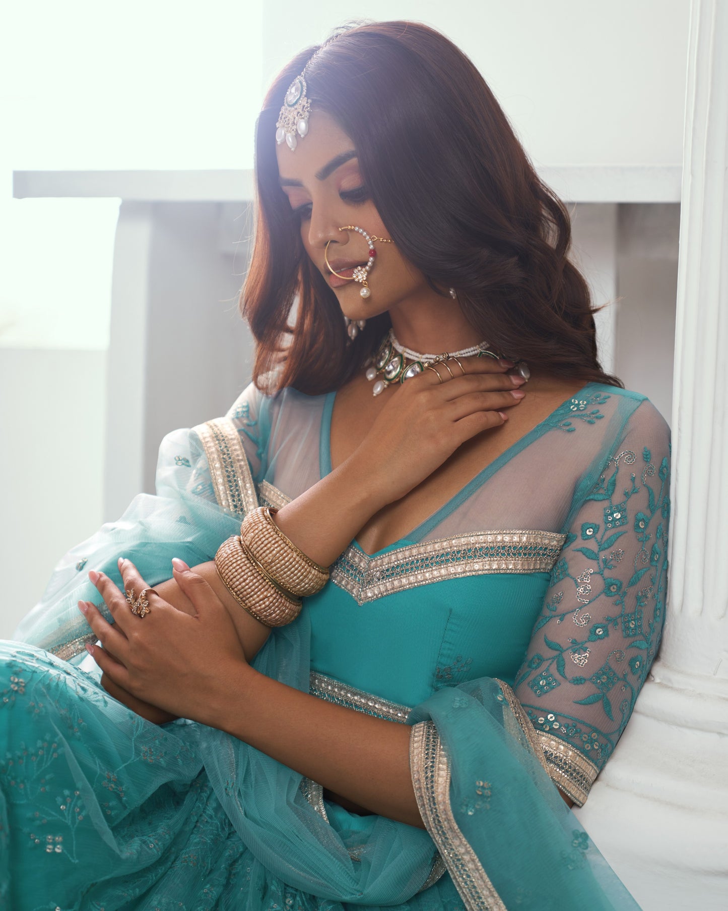 Woman in a turquoise traditional outfit with jewelry indoors