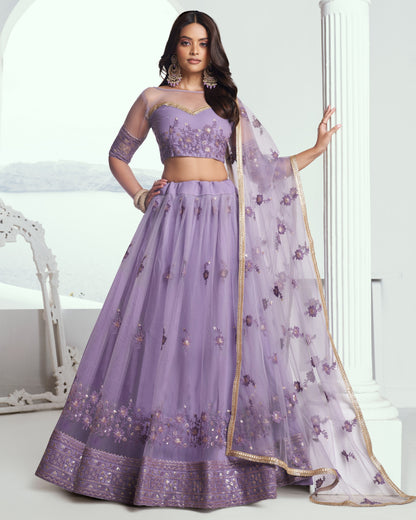 Woman wearing a purple embroidered lehenga with a white background