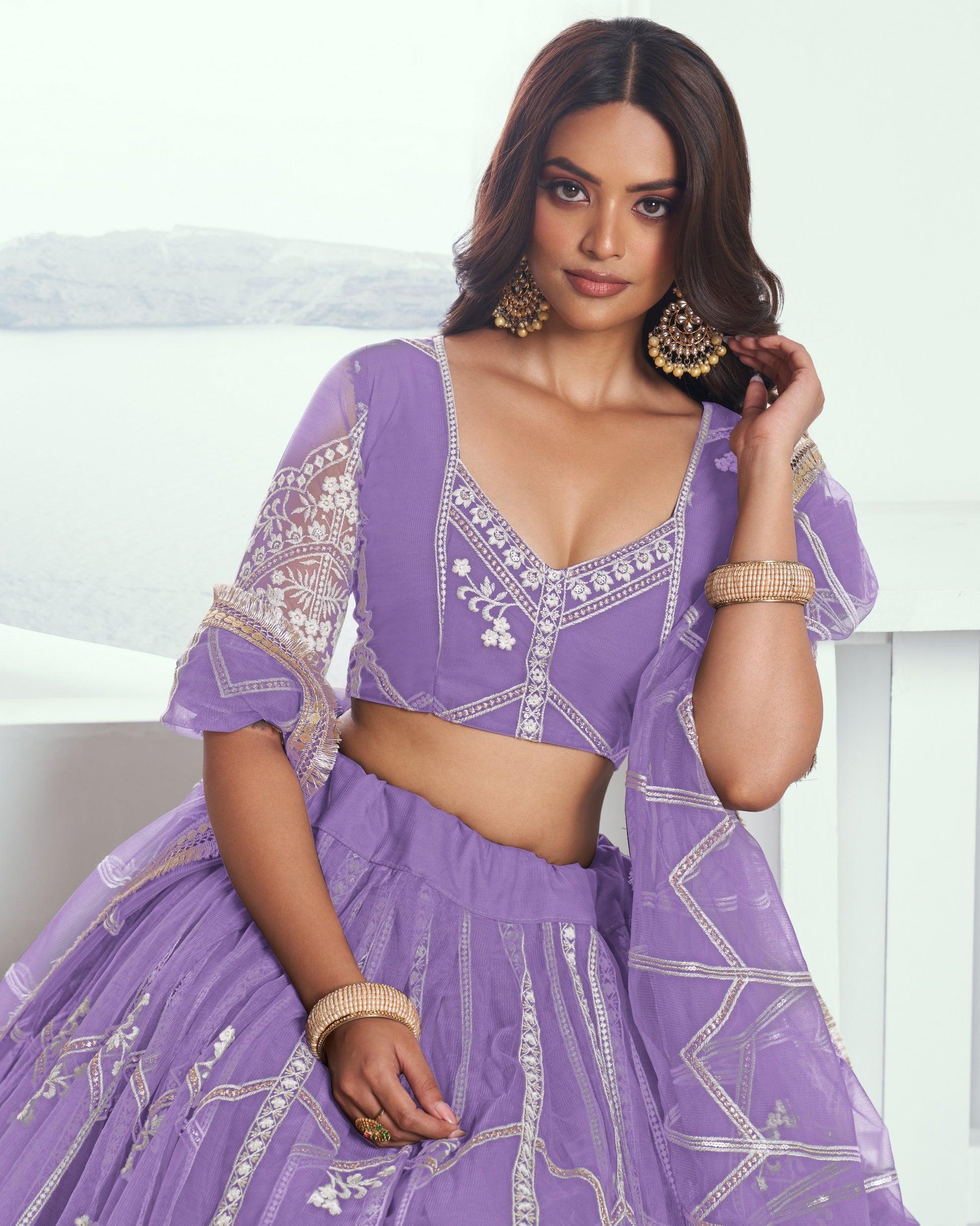 Woman wearing a purple embroidered traditional outfit with a white background